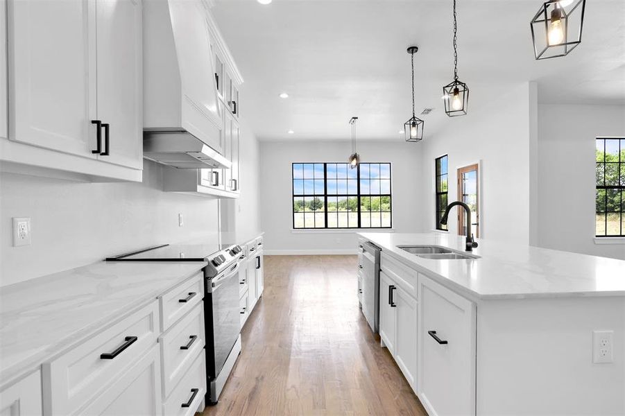 Kitchen with light hardwood / wood-style flooring, stainless steel appliances, a center island with sink, sink, and custom exhaust hood