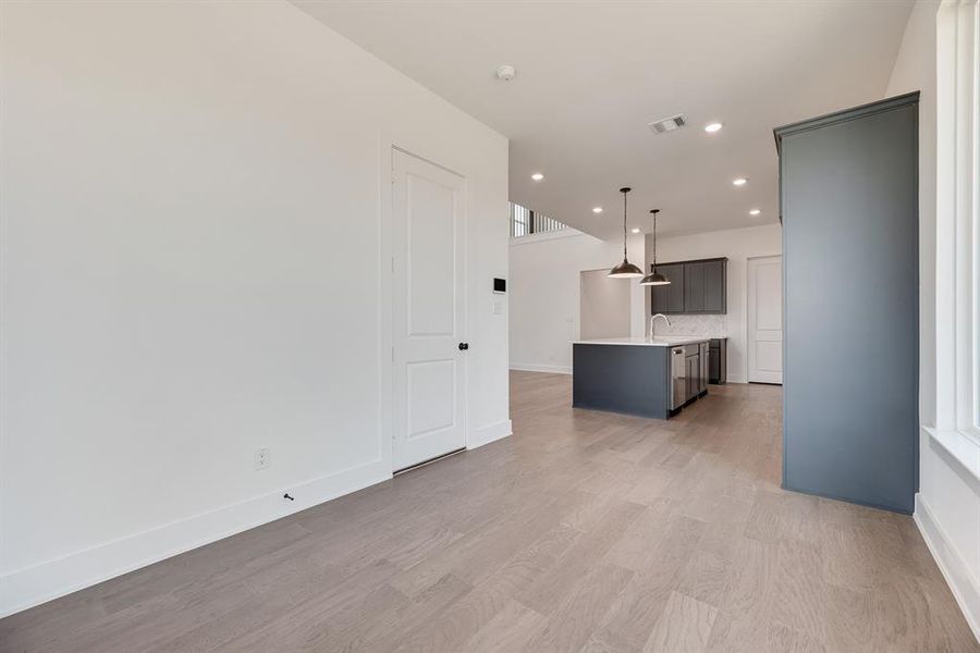Kitchen featuring an island with sink, decorative light fixtures, light wood-style flooring, recessed lighting, and light stone countertops Kitchen featuring an island with sink, decorative light fixtures, light wood-style flooring, recessed lighting, and light stone countertops