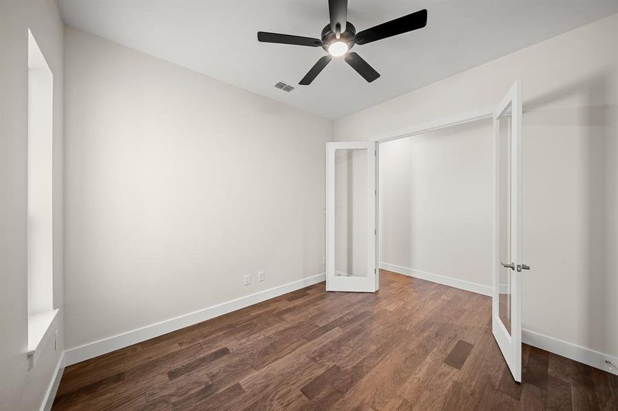 Unfurnished bedroom featuring dark wood-type flooring, ceiling fan, and french doors