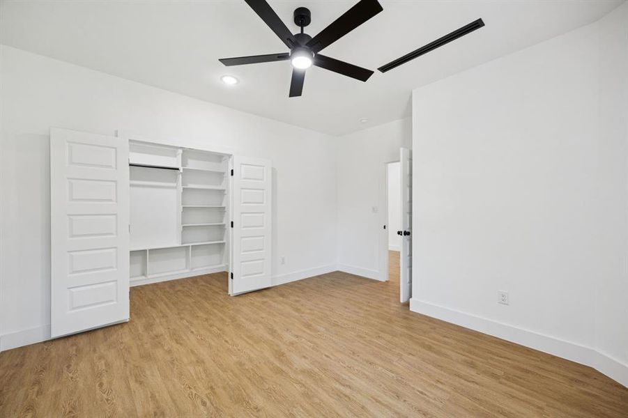 Unfurnished bedroom featuring a spacious closet, light wood-style floors, a ceiling fan, and recessed lighting