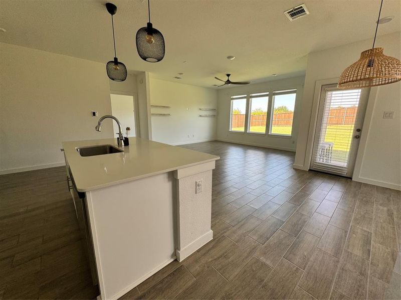 Kitchen with decorative light fixtures, a center island with sink, open floor plan, wood finish floors, and white cabinets Kitchen with decorative light fixtures, a center island with sink, open floor plan, wood finish floors, and white cabinets