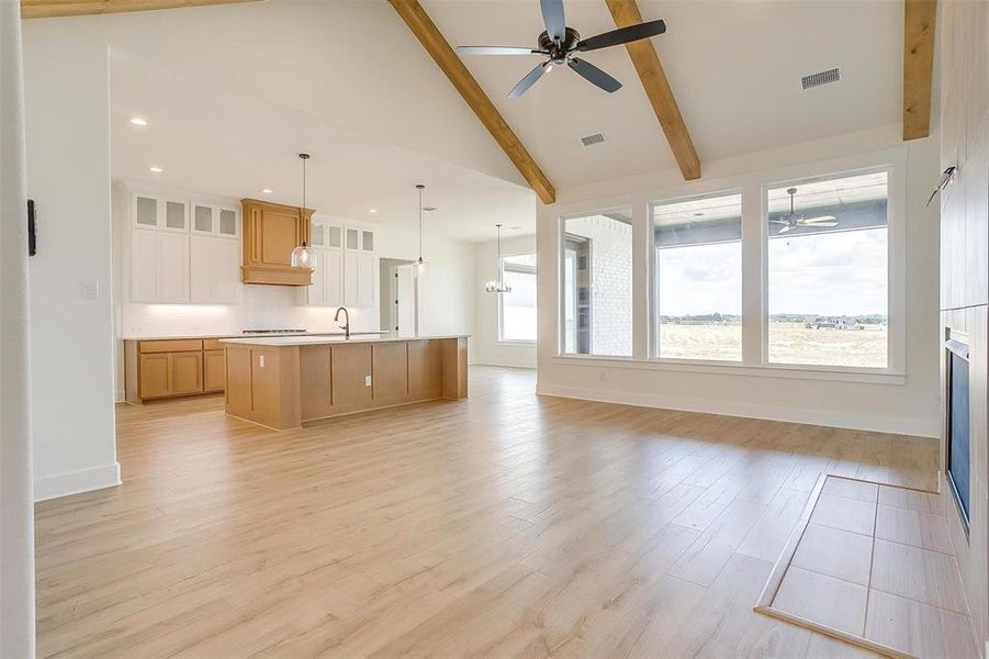 Kitchen featuring light wood-type flooring, pendant lighting, ceiling fan, beam ceiling, and a large island