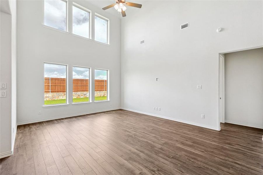 Empty room featuring wood-type flooring, ceiling fan, and a towering ceiling