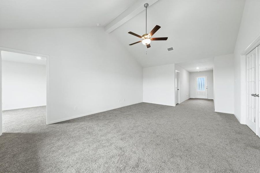 Empty room with beamed ceiling, light carpet, a ceiling fan, and high vaulted ceiling