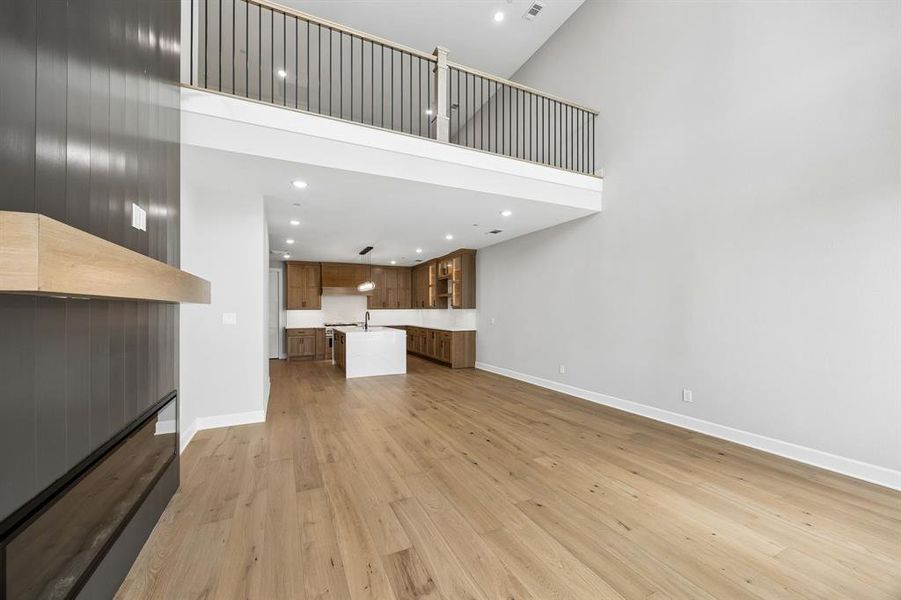 Unfurnished living room featuring a high ceiling, light wood-style flooring, and recessed lighting Unfurnished living room featuring a high ceiling, light wood-style flooring, and recessed lighting