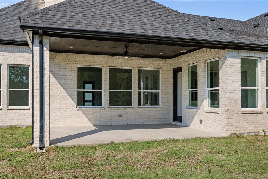 Covered concrete patio featuring a ceiling fan, recessed lighting, and white brick exterior