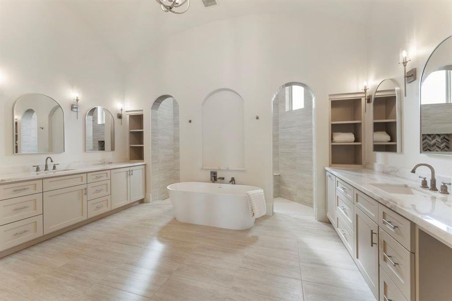 This is a spacious spa retreat ensuite features dual vanity sinks, freestanding tub, and elegant archways. The room is finished with neutral tones and luxurious materials, creating a serene and sophisticated space.