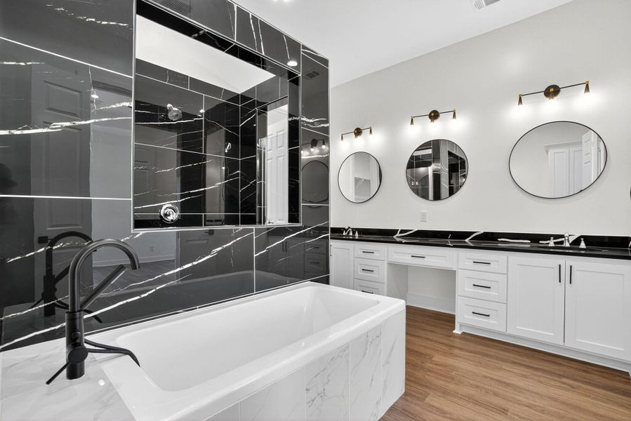Full bath featuring double vanity, a freestanding bath, light wood finished floors, and a shower Full bath featuring double vanity, a freestanding bath, light wood finished floors, and a shower