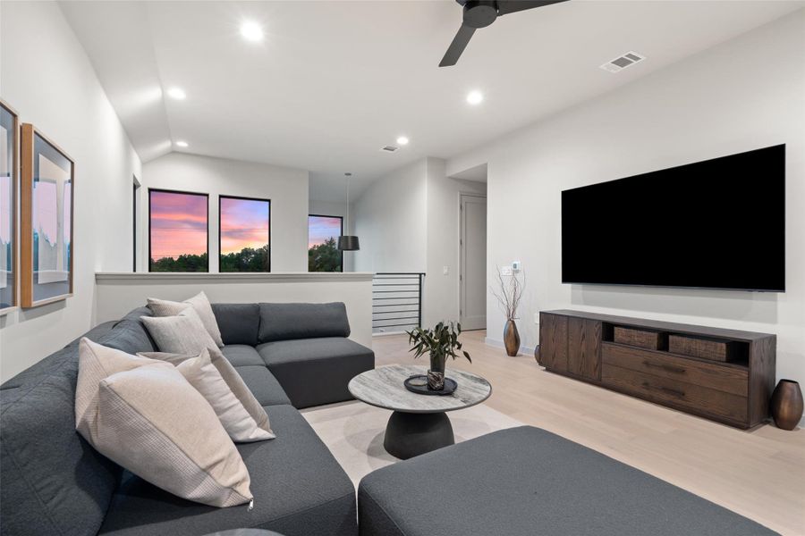 Sun-filled living area features soaring ceilings and light wood flooring. Sun-filled living area features soaring ceilings and light wood flooring.