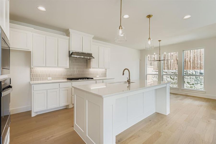 Kitchen featuring range hood, tasteful backsplash, light wood finished floors, recessed lighting, and white cabinets