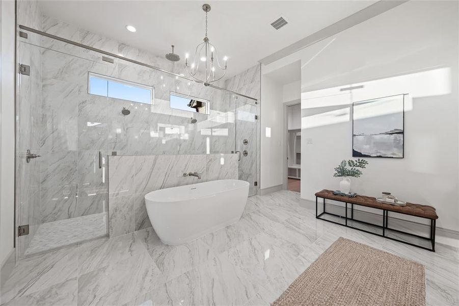 Bathroom with a marble finish shower, a freestanding tub, a chandelier, and light marble finish flooring Bathroom with a marble finish shower, a freestanding tub, a chandelier, and light marble finish flooring