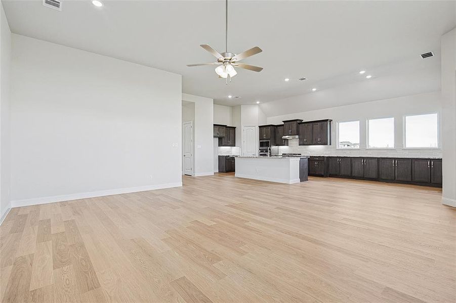 Unfurnished living room featuring ceiling fan, light wood-style flooring, recessed lighting, and vaulted ceiling
