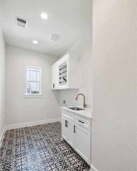 Laundry room with washer hookup, cabinets, tile patterned floors, and sink