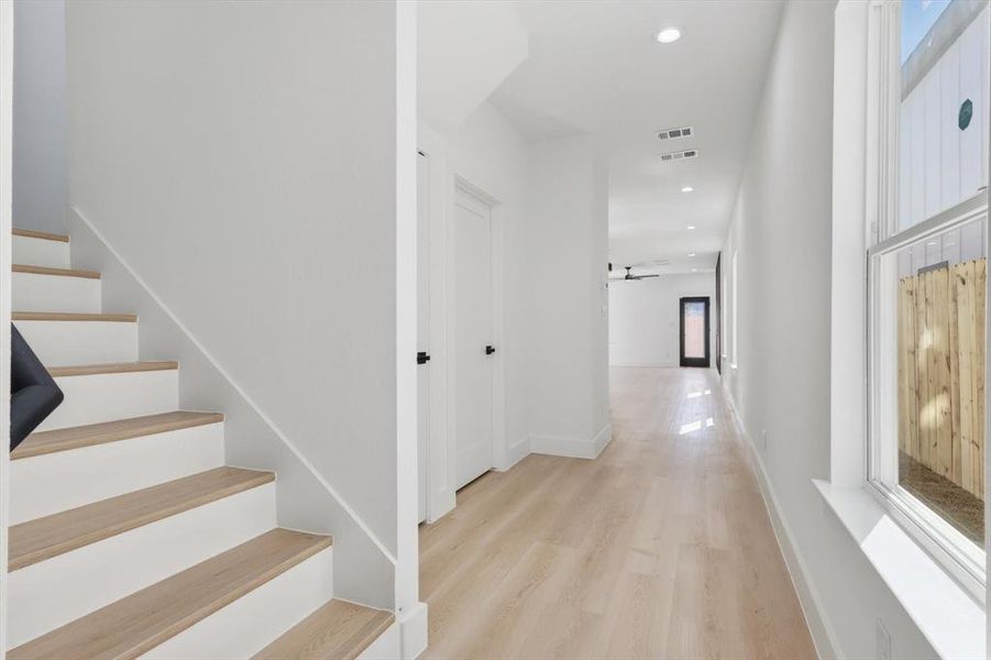 Hall with recessed lighting, light wood-style floors, and stairway