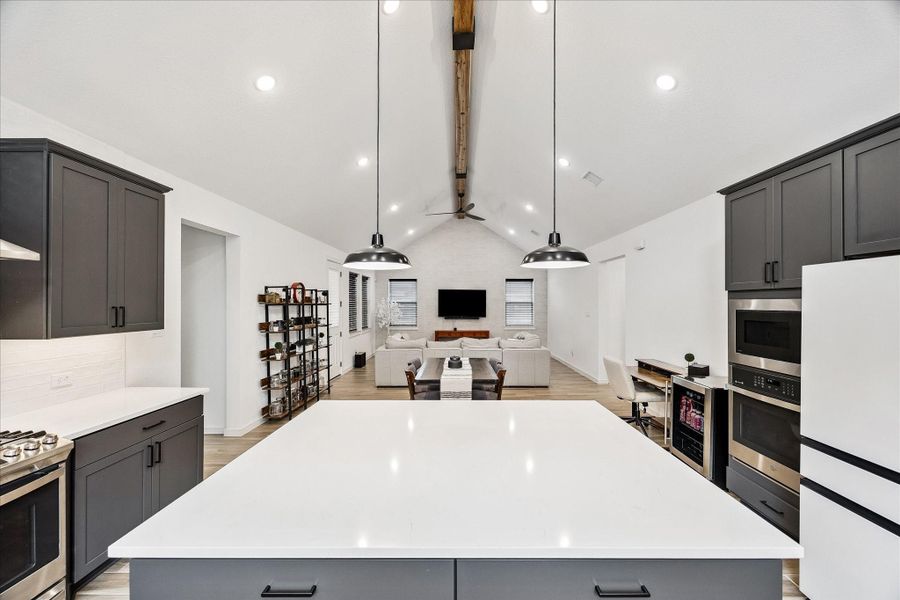 Large quartz waterfall-style island with seating, matte black hardware, and abundant prep space, serving as the centerpiece of the home.