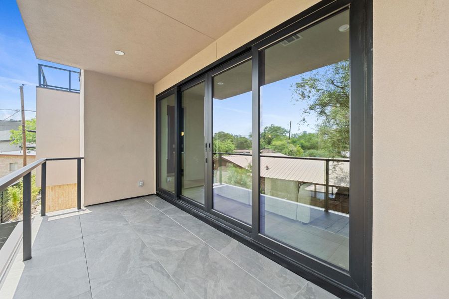 A spacious outdoor terrace features sleek glass railings and large sliding doors. A spacious outdoor terrace features sleek glass railings and large sliding doors.