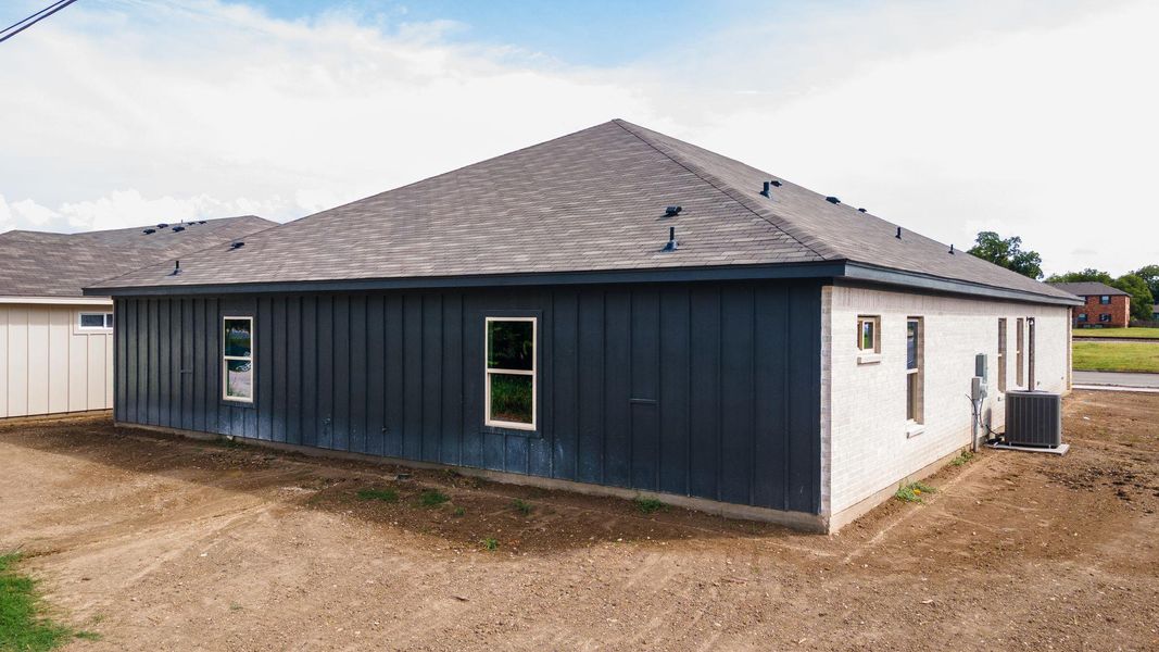 View of side of home with board and batten siding and a shingled roof