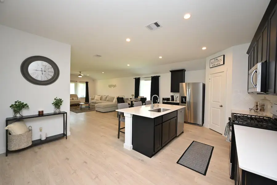 This open-concept living space features a modern kitchen with a central island, stainless steel appliances, and sleek cabinetry. The adjacent living area is spacious with ample natural light and perfect for entertaining or relaxing. This open-concept living space features a modern kitchen with a central island, stainless steel appliances, and sleek cabinetry. The adjacent living area is spacious with ample natural light and perfect for entertaining or relaxing.