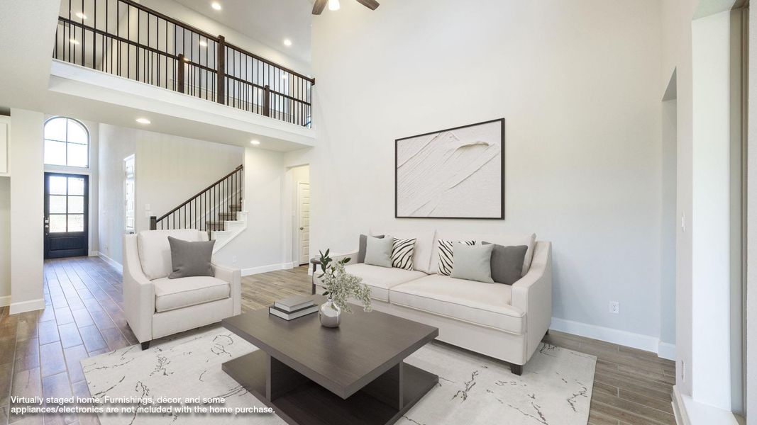 Living room featuring wood finished floors, a high ceiling, recessed lighting, and stairway Living room featuring wood finished floors, a high ceiling, recessed lighting, and stairway