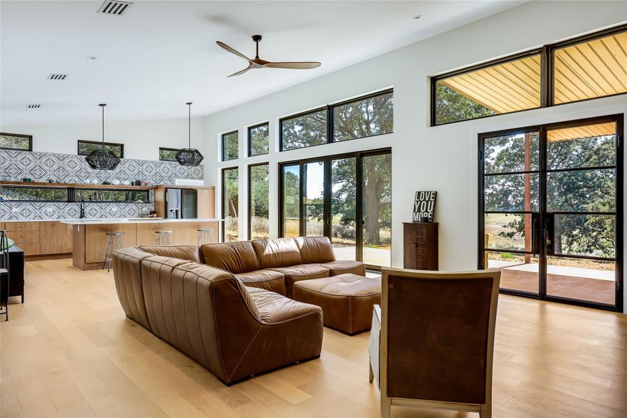 Living room with light wood-style floors, a ceiling fan, and a high ceiling