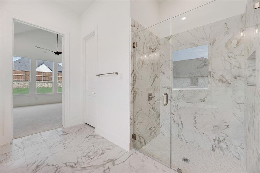 Full bathroom featuring marble look tile flooring and a marble finish shower