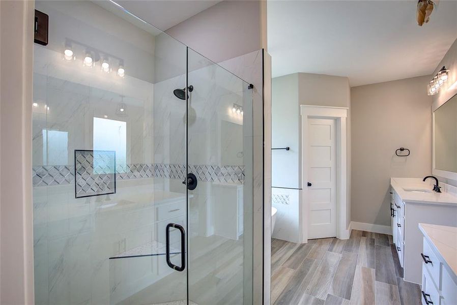 Bathroom with a shower with door, vanity, and hardwood / wood-style floors Bathroom with a shower with door, vanity, and hardwood / wood-style floors