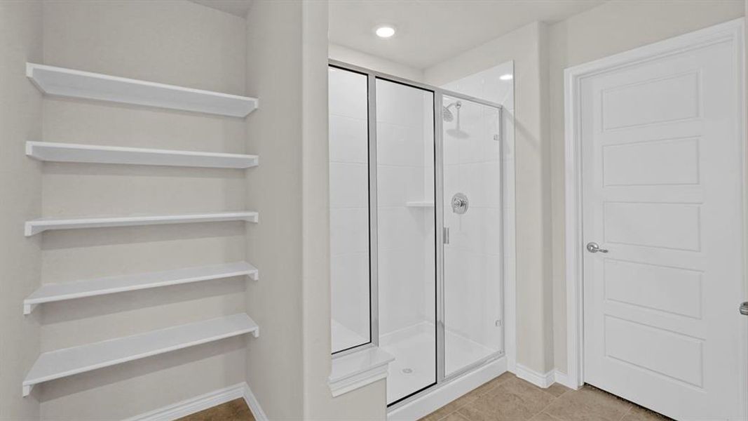 Shower enclosure with glass door, chrome fixtures, and a white tiled interior