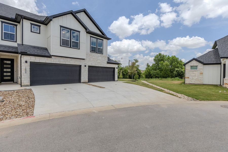 A contemporary duplex with strong curb appeal features a black and white exterior with stone accents and dual garage access. A contemporary duplex with strong curb appeal features a black and white exterior with stone accents and dual garage access.