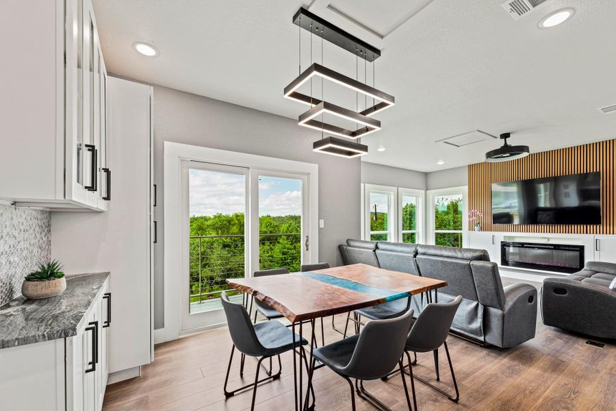 Open-concept interior featuring light wood-finish flooring, recessed lighting, and a modern linear chandelier