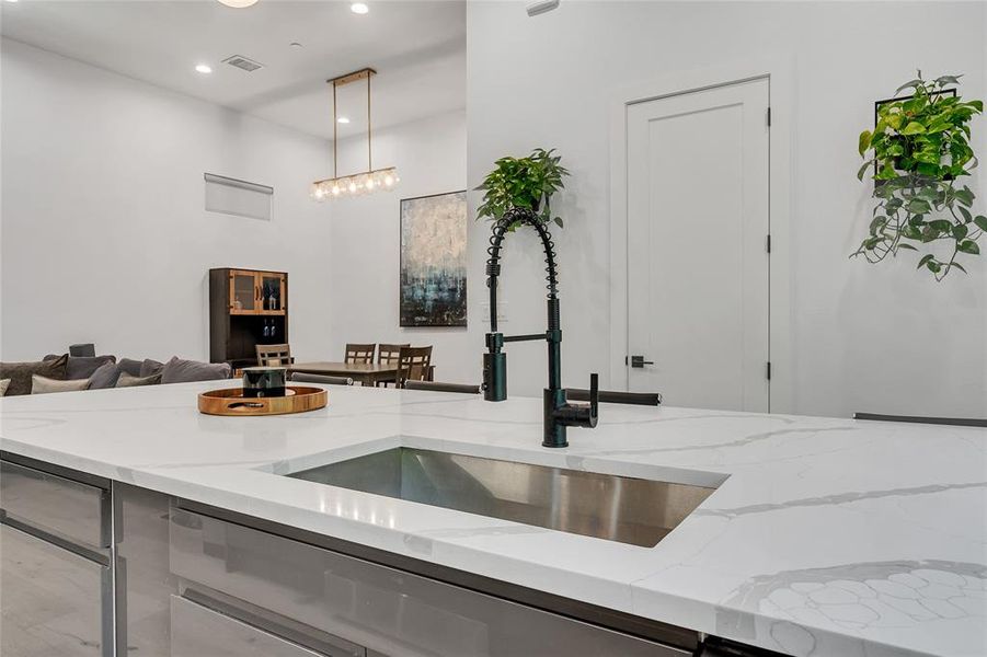 Kitchen with light stone counters, pendant lighting, open floor plan, and recessed lighting Kitchen with light stone counters, pendant lighting, open floor plan, and recessed lighting