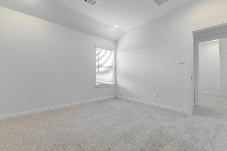 Comfortable secondary bedroom with soft carpet, neutral finishes, recessed lighting, and a window with blinds. The room offers a practical layout with easy hallway access and enough open wall space for a bed, desk, dresser, or customized furniture arrangement.