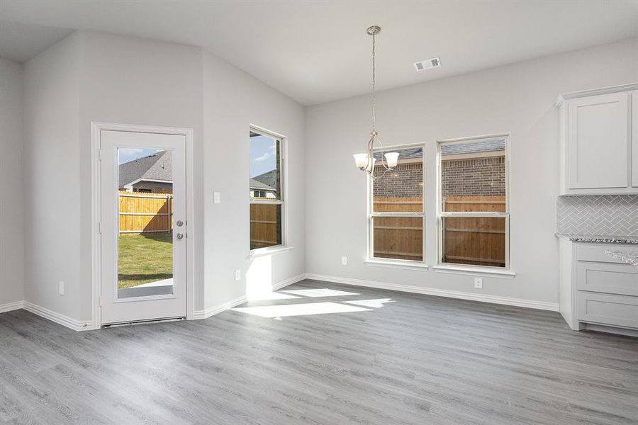 Unfurnished dining area with a chandelier and light wood-type flooring