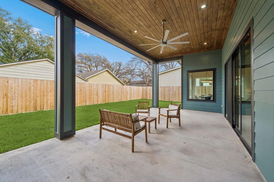This huge back covered patio has a wood paneled ceiling and fan. It's plumbed for an outdoor kitchen.