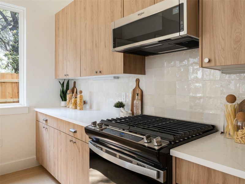 Modern kitchen featuring light wood-finish cabinetry, white countertops, and a white subway tile backsplash