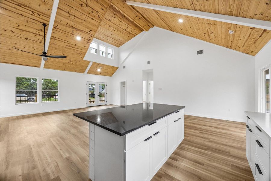 An open concept living area boasts vaulted wooden ceilings, rich flooring, and a central kitchen island. An open concept living area boasts vaulted wooden ceilings, rich flooring, and a central kitchen island.