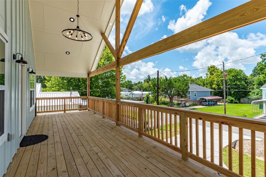 30-foot covered patio/deck with high vaulted ceiling, wood beam accents, exterior coach lights and attractive light fixture.