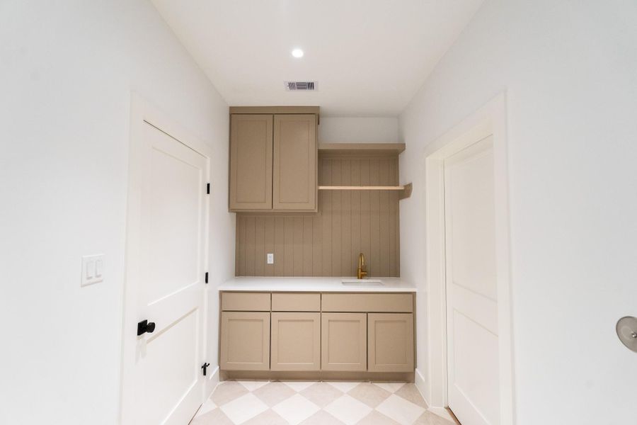 Designer laundry room featuring custom cabinetry & checked flooring