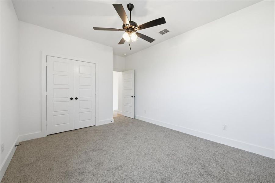 Unfurnished bedroom with carpet flooring, a closet, and ceiling fan Unfurnished bedroom with carpet flooring, a closet, and ceiling fan
