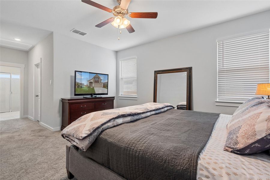 Bedroom with light carpet, multiple windows, baseboards, and a ceiling fan Bedroom with light carpet, multiple windows, baseboards, and a ceiling fan