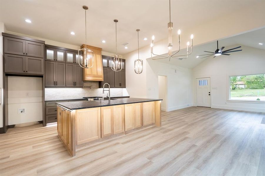 Kitchen with an island with sink, sink, light hardwood / wood-style flooring, and vaulted ceiling