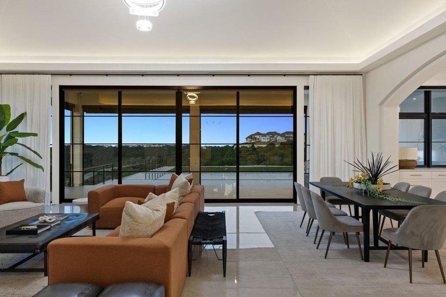 An open-concept interior features floor-to-ceiling windows offering scenic hillside views and an abundance of natural light.