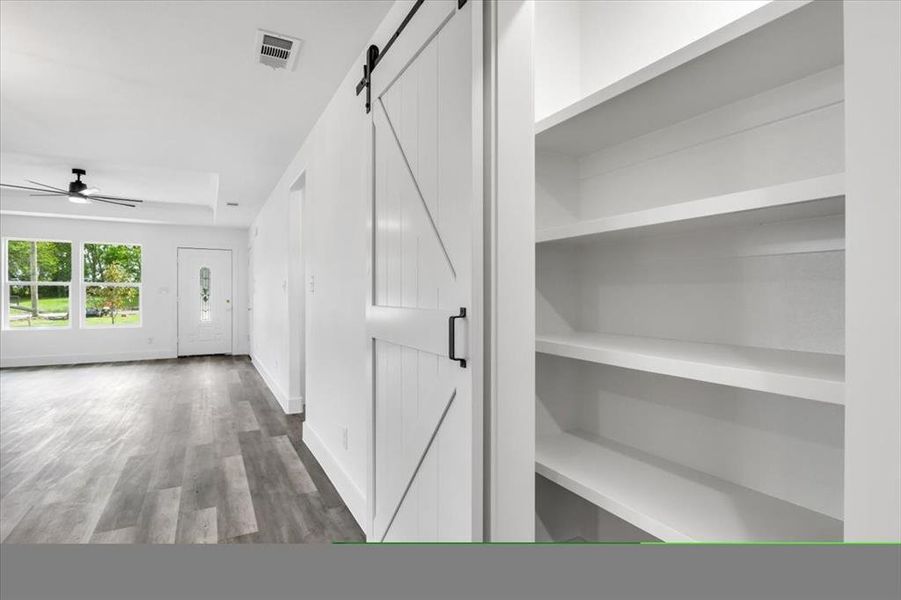 Hallway featuring dark wood-type flooring and a barn door