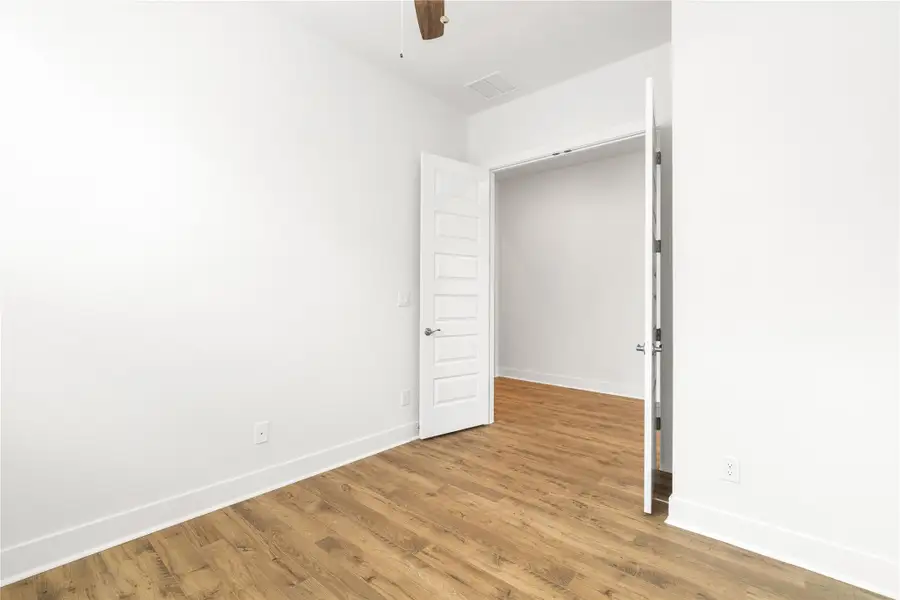 A bedroom showcases clean lines and durable wood flooring, offering a fresh canvas for personalization. A bedroom showcases clean lines and durable wood flooring, offering a fresh canvas for personalization.