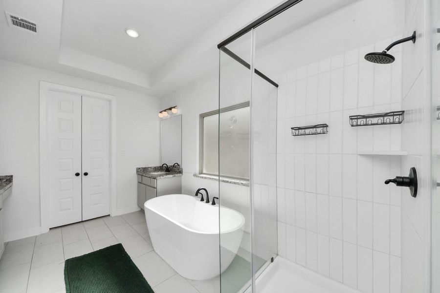 This modern bathroom features a sleek freestanding tub, a glass-enclosed shower with black fixtures, dual vanities, and a spacious layout with a clean, white design. Ideal for a contemporary home. This modern bathroom features a sleek freestanding tub, a glass-enclosed shower with black fixtures, dual vanities, and a spacious layout with a clean, white design. Ideal for a contemporary home.