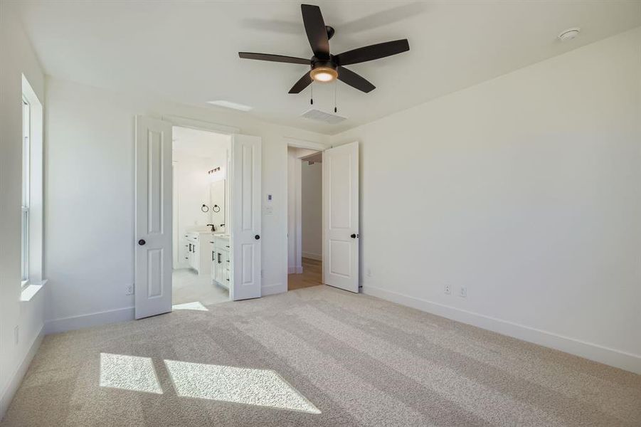 Unfurnished bedroom featuring light colored carpet, connected bathroom, and ceiling fan Unfurnished bedroom featuring light colored carpet, connected bathroom, and ceiling fan
