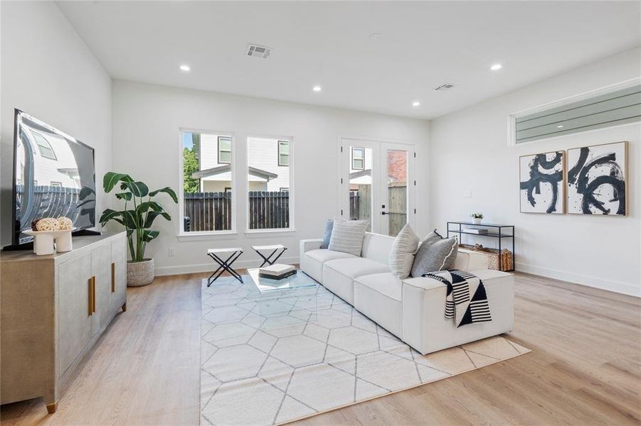 Bright and spacious living room featuring sleek hardwood floors, modern furnishings, and abundant natural light from large windows and glass doors. Bright and spacious living room featuring sleek hardwood floors, modern furnishings, and abundant natural light from large windows and glass doors.