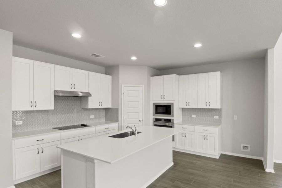 Image of a kitchen with a white center island and cabinetry with stainless steel appliances Image of a kitchen with a white center island and cabinetry with stainless steel appliances