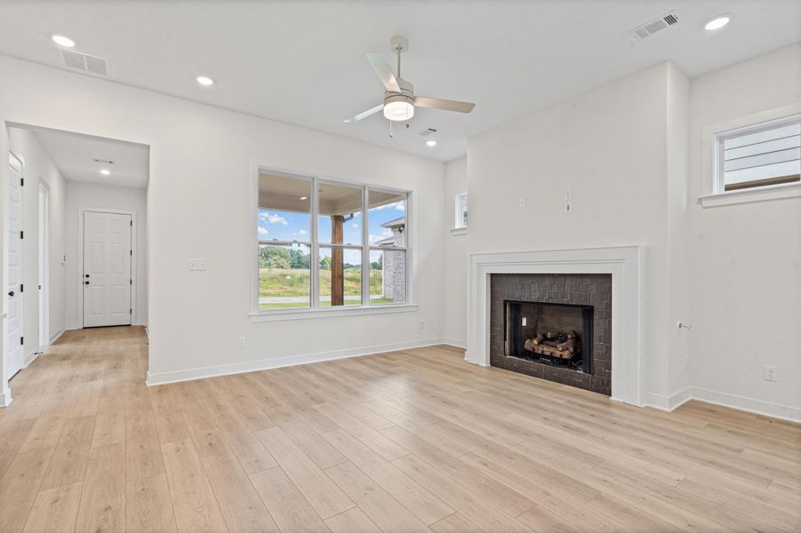 Spacious living area featuring light wood-finish flooring, a contemporary ceiling fan, and recessed lighting Spacious living area featuring light wood-finish flooring, a contemporary ceiling fan, and recessed lighting