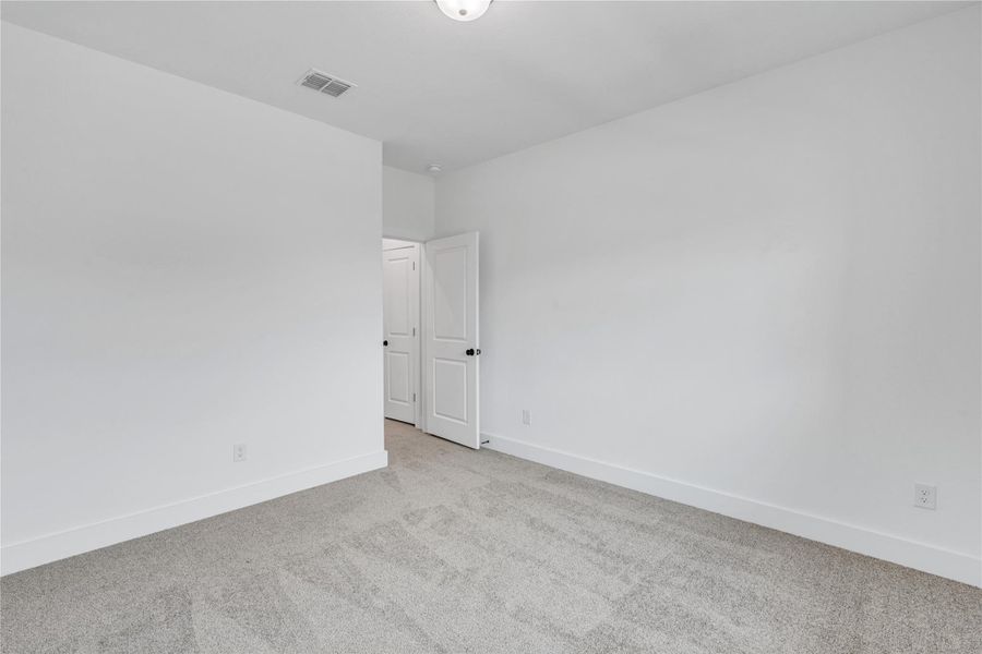A spacious, neutral room offers a clean canvas for personalized living with soft carpeting.