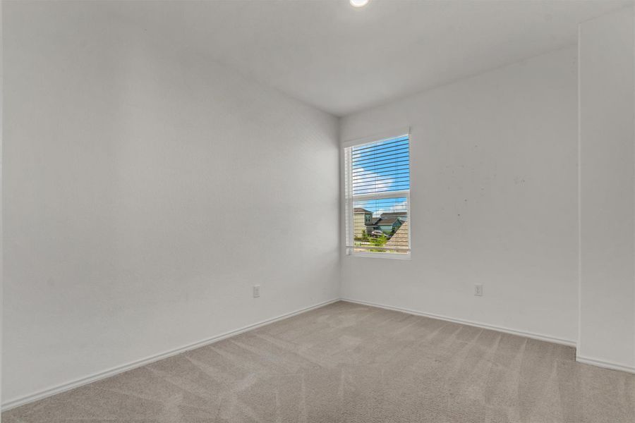 A single window provides natural light to this carpeted bedroom with clean white walls. A single window provides natural light to this carpeted bedroom with clean white walls.